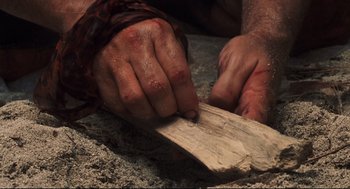 Movie still from “Cast Away” (2000), directed by Robert Zemeckis – A person is holding a piece of wood; Extreme Close Up shot, Overhead angle