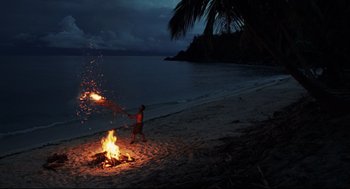Movie still from “Cast Away” (2000), directed by Robert Zemeckis – A man standing next to a fire on the beach; Extreme Wide shot, High angle