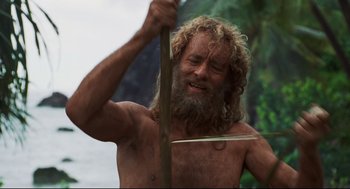 Movie still from “Cast Away” (2000), directed by Robert Zemeckis – A man with long hair and a beard holding a sword; Medium shot, Low angle