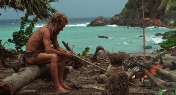 Movie still from “Cast Away” (2000), directed by Robert Zemeckis – A man sitting on a rock by the ocean; Wide shot, High angle