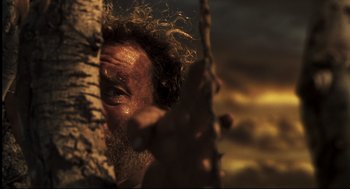 Movie still from “Cast Away” (2000), directed by Robert Zemeckis – A man's face as he peers out from behind a tree; Close Up shot, Low angle