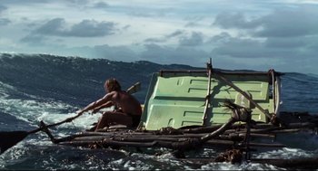 Movie still from “Cast Away” (2000), directed by Robert Zemeckis – A man sitting on top of a raft in the ocean; Wide shot, Low angle