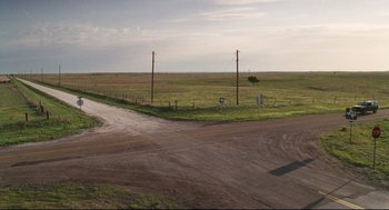 Movie still from “Cast Away” (2000), directed by Robert Zemeckis – A dirt road going through an empty field; Extreme Wide shot, High angle