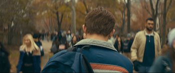 Movie still from “Cherry” (2021), directed by Joe Russo – A man with a backpack walking in a crowd of onlookers; Close Up shot, Over the shoulder angle
