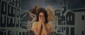 Movie still from “Cherry” (2021), directed by Joe Russo – A woman covers her face with her hands in front of mountains; Medium shot, High angle