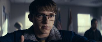 Movie still from “Cherry” (2021), directed by Joe Russo – A young man wearing glasses looking at the camera; Close Up shot, Over the shoulder angle