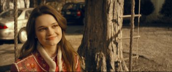 Movie still from “Cherry” (2021), directed by Joe Russo – A young woman smiling in front of a tree; Close Up shot, Over the shoulder angle