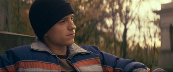 Movie still from “Cherry” (2021), directed by Joe Russo – A young man wearing a hat and a jacket; Close Up shot, Over the shoulder angle
