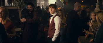 Movie still from “Cherry” (2021), directed by Joe Russo – A man in a red vest and white shirt standing in front of a group of people; Medium shot, Over the shoulder angle