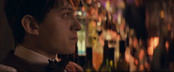 Movie still from “Cherry” (2021), directed by Joe Russo – A young man looking into the distance in front of a bar; Close Up shot, Over the shoulder angle