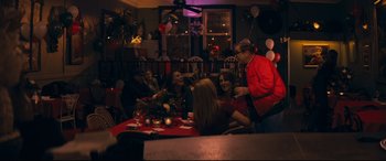Movie still from “Cherry” (2021), directed by Joe Russo – A group of people sitting around a table at a party; Medium shot, Over the shoulder angle