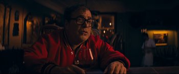 Movie still from “Cherry” (2021), directed by Joe Russo – A man sitting at a table with a glass of wine; Close Up shot, Low angle