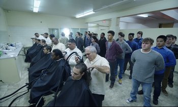 Movie still from “Cherry” (2021), directed by Joe Russo – A group of men standing in a room with their backs to the camera; Wide shot, High angle
