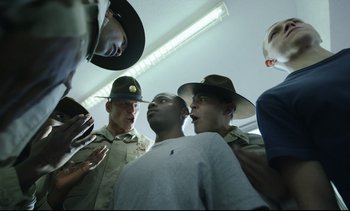 Movie still from “Cherry” (2021), directed by Joe Russo – A group of men standing next to each other in a room; Close Up shot, Low angle