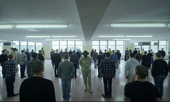 Movie still from “Cherry” (2021), directed by Joe Russo – A group of people standing in a large room; Wide shot, High angle