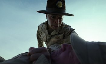 Movie still from “Cherry” (2021), directed by Joe Russo – A man in a uniform looking down at someone's hand; Close Up shot, Low angle