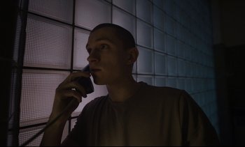 Movie still from “Cherry” (2021), directed by Joe Russo – A man talking on a phone in a dark room; Close Up shot, Low angle