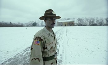 Movie still from “Cherry” (2021), directed by Joe Russo – A man in uniform standing in the middle of a snow covered field; Medium shot, Low angle