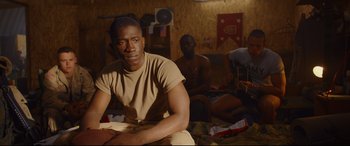 Movie still from “Cherry” (2021), directed by Joe Russo – A man sitting on the ground in a room; Medium shot, Over the shoulder angle