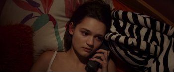 Movie still from “Cherry” (2021), directed by Joe Russo – A woman is talking on a cell phone while laying in bed; Close Up shot, High angle