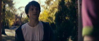 Movie still from “Cherry” (2021), directed by Joe Russo – A young man standing in front of a tree; Close Up shot, Over the shoulder angle