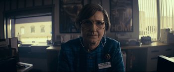 Movie still from “Cherry” (2021), directed by Joe Russo – An older woman wearing glasses and a blue shirt; Close Up shot, Low angle
