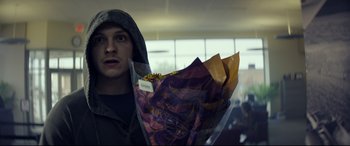 Movie still from “Cherry” (2021), directed by Joe Russo – A man holding a bouquet of flowers while wearing a hoodie; Close Up shot, Over the shoulder angle