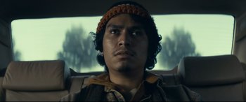 Movie still from “Cherry” (2021), directed by Joe Russo – A man with a beard and a hat in the back of a car; Close Up shot, Low angle