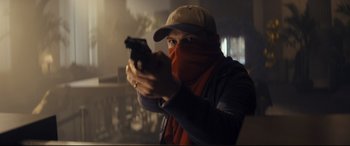 Movie still from “Cherry” (2021), directed by Joe Russo – A man holding a gun wearing a hat and a scarf; Close Up shot, Low angle