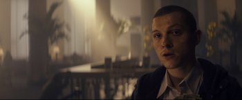 Movie still from “Cherry” (2021), directed by Joe Russo – A man in a suit is looking at the camera; Close Up shot, Over the shoulder angle