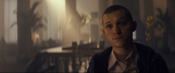 Movie still from “Cherry” (2021), directed by Joe Russo – A young man with a shaved head is posing for a picture; Close Up shot, Over the shoulder angle