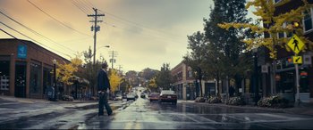Movie still from “Cherry” (2021), directed by Joe Russo – A man crossing a street on a rainy day; Extreme Wide shot, Low angle