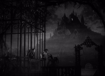 Movie still from “Citizen Kane” (1941), directed by Orson Welles – Two people sitting on a fence in front of a castle; Extreme Wide shot, High angle
