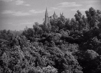 Movie still from “Citizen Kane” (1941), directed by Orson Welles – A black - and - white photo of trees and a church in the background; Extreme Wide shot, High angle
