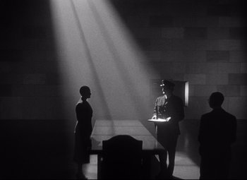 Movie still from “Citizen Kane” (1941), directed by Orson Welles – A man and a woman are standing in front of a podium; Wide shot, Low angle