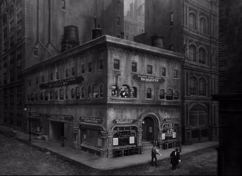 Movie still from “Citizen Kane” (1941), directed by Orson Welles – An old photo of a building with people standing outside; Extreme Wide shot, High angle