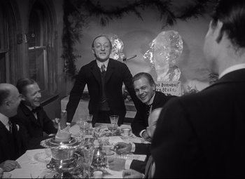 Movie still from “Citizen Kane” (1941), directed by Orson Welles – A group of people sitting at a table with food; Medium shot, Over the shoulder angle