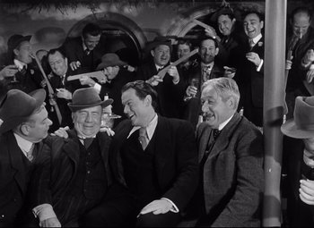 Movie still from “Citizen Kane” (1941), directed by Orson Welles – A group of men sitting next to each other in a room; Medium shot, High angle