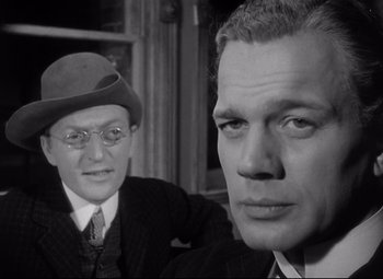 Movie still from “Citizen Kane” (1941), directed by Orson Welles – A man and a man in a suit and hat; Close Up shot, Over the shoulder angle