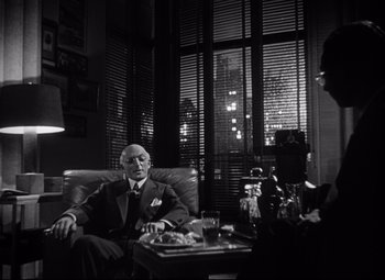 Movie still from “Citizen Kane” (1941), directed by Orson Welles – A man sitting in a chair in front of another man; Medium shot, Over the shoulder angle