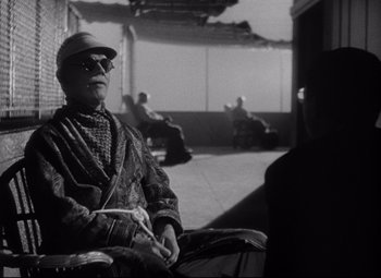 Movie still from “Citizen Kane” (1941), directed by Orson Welles – An older man sitting on a bench in a courtyard; Medium shot, Low angle