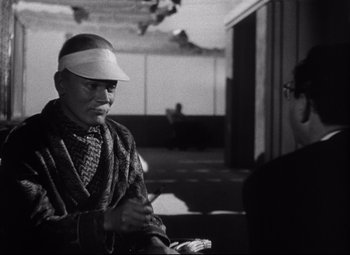 Movie still from “Citizen Kane” (1941), directed by Orson Welles – An older man wearing a hat and a scarf; Medium shot, Over the shoulder angle