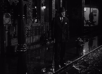 Movie still from “Citizen Kane” (1941), directed by Orson Welles – A black and white photo of a man in a suit and hat; Wide shot, High angle