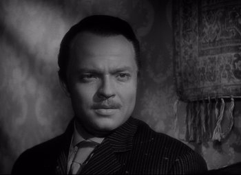 Movie still from “Citizen Kane” (1941), directed by Orson Welles – A man in a suit and tie in front of a wall; Close Up shot, Low angle