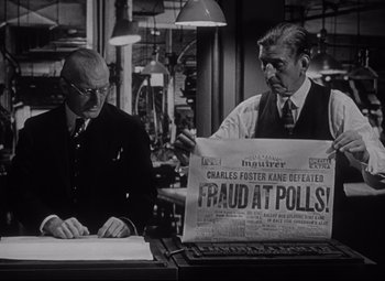 Movie still from “Citizen Kane” (1941), directed by Orson Welles – Two men in a room with papers and a newspaper on a desk; Medium shot, Low angle