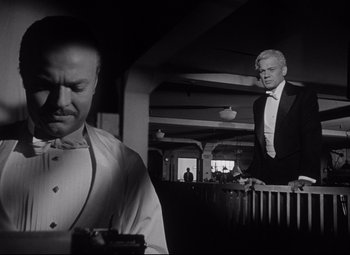 Movie still from “Citizen Kane” (1941), directed by Orson Welles – A man in a tuxedo standing next to another man in a suit; Medium shot, Low angle