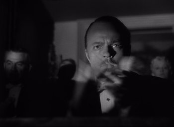 Movie still from “Citizen Kane” (1941), directed by Orson Welles – A black - and - white photo of a man smoking a cigarette; Close Up shot, Low angle