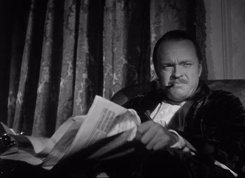 Movie still from “Citizen Kane” (1941), directed by Orson Welles – A black and white photo of a man smoking a cigarette and reading a newspaper; Close Up shot, Low angle