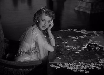 Movie still from “Citizen Kane” (1941), directed by Orson Welles – An old black and white photo of a woman sitting at a table; Medium shot, High angle