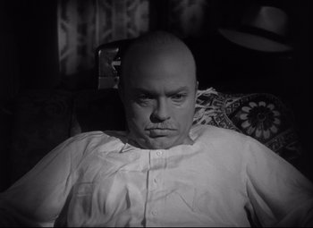 Movie still from “Citizen Kane” (1941), directed by Orson Welles – A man with a shaved head and a white shirt; Close Up shot, High angle